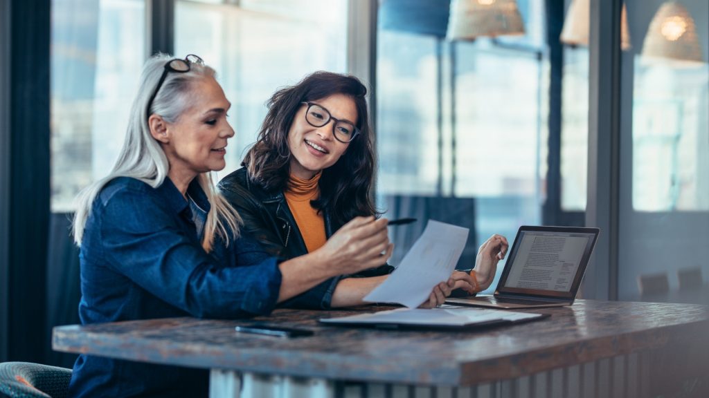 2 women sitting at a desk discussing business solutions